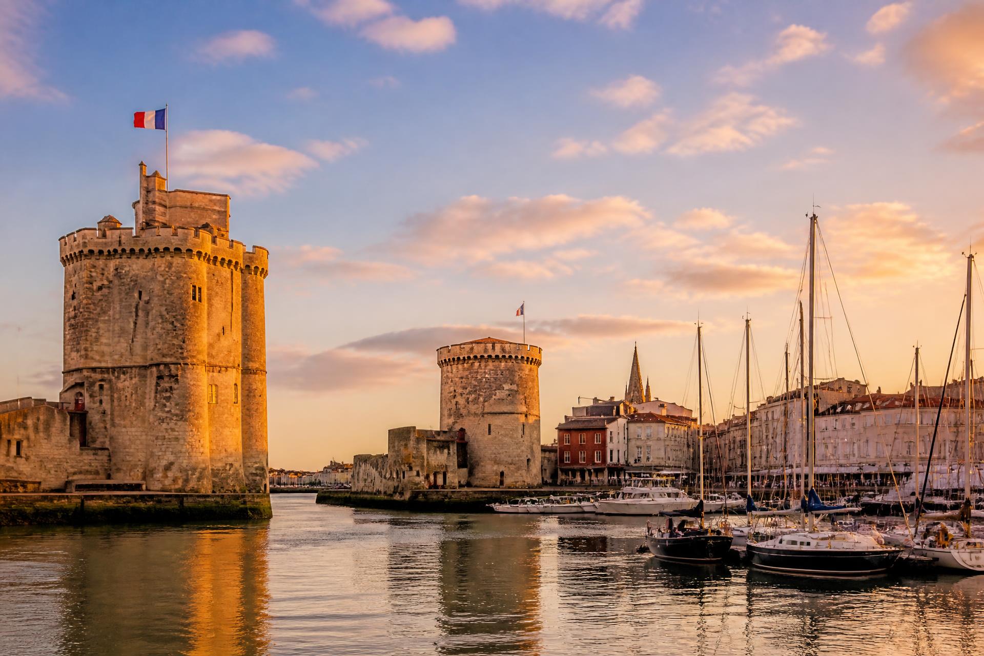Le Vieux-Port de La Rochelle au coucher du soleil, ses tours médiévales et les mâts des voiliers