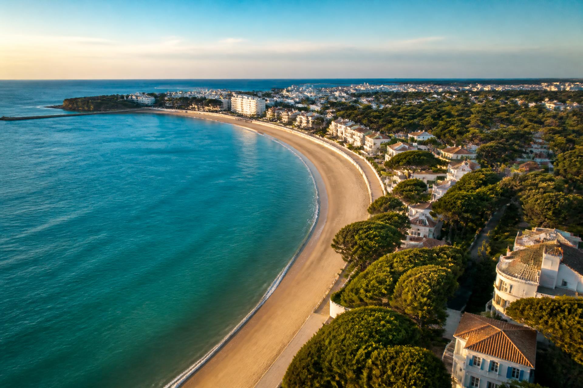 Vue aérienne de Royan, la plage de la Grande Conche et les villas balnéaires bordées de pins au coucher du soleil